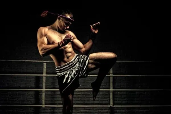 Muay Thai fighter performing a traditional stance inside the ring, showcasing technique and balance.
