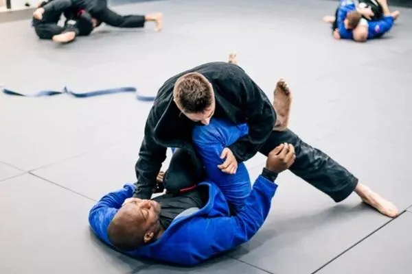 Brazilian Jiu-Jitsu training session with fighters practicing grappling techniques on the mat.