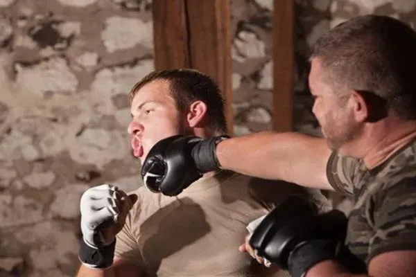 MMA fighter taking a strong punch to the chin during sparring, demonstrating durability and impact resistance.