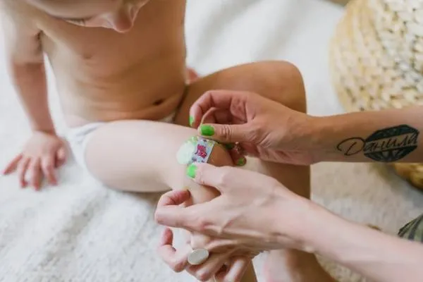 kid and a woman applying a band aid