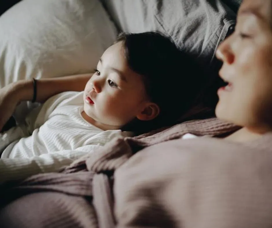a child and a woman laying in bed