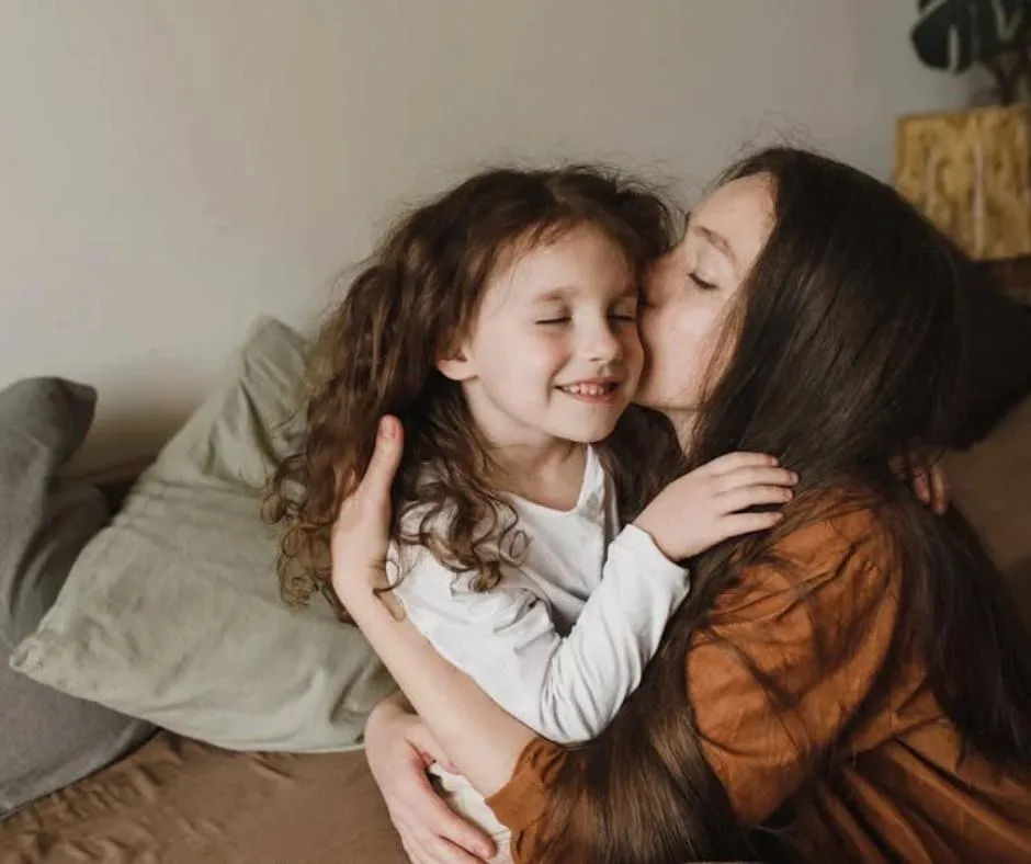 a mother kissing her daughter