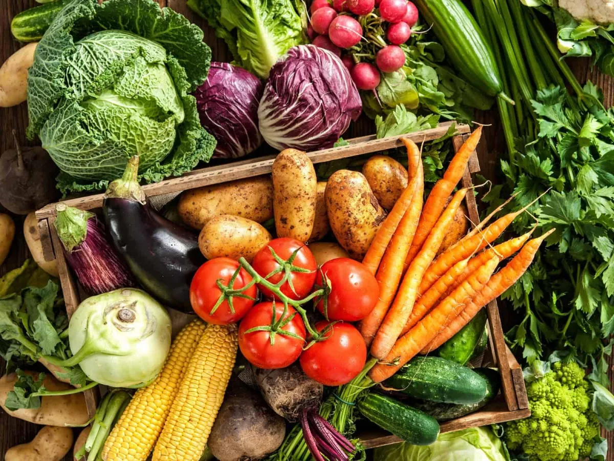 Fresh fruits and vegetables grouped by season on a wooden table.