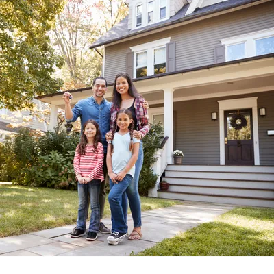 Smiling family of four standing proudly in front of their new home, symbolizing homeownership and generational wealth building.