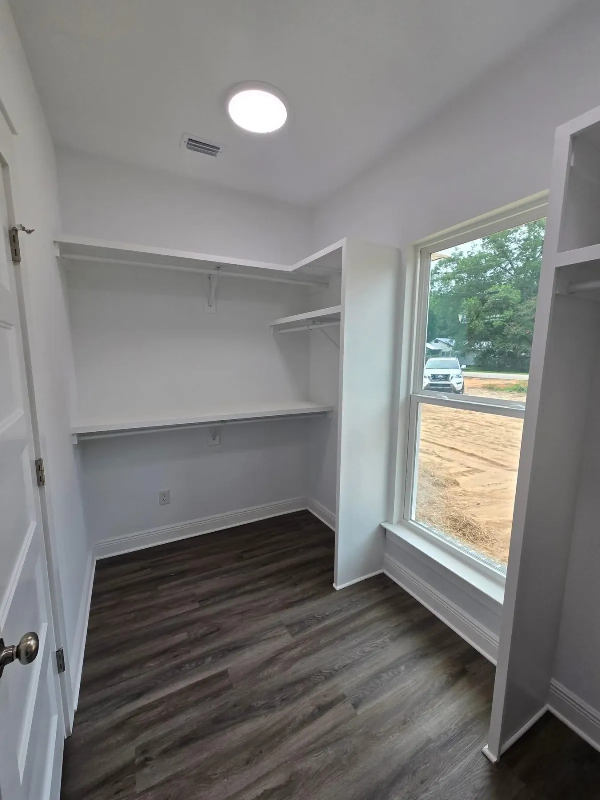 Walk in closet with white walls, shelves and hardwood flooring