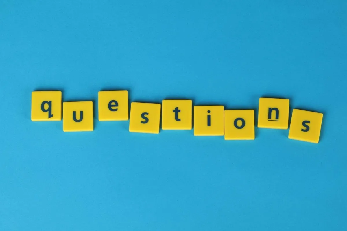 Wooden letter blocks spelling out the word "questions" arranged on a bright blue background, representing the importance of asking good interview questions