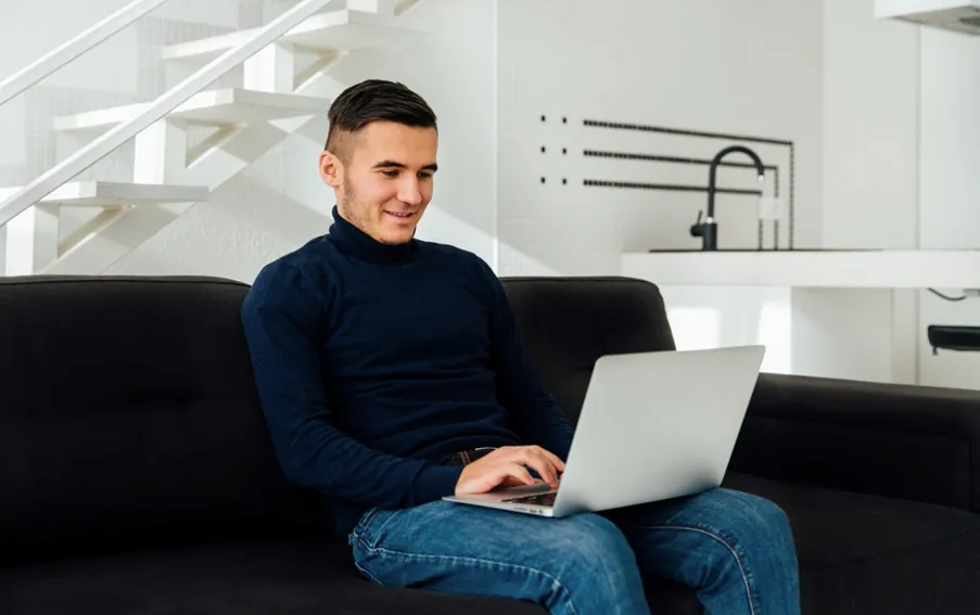 A businessman working on a laptop at home.