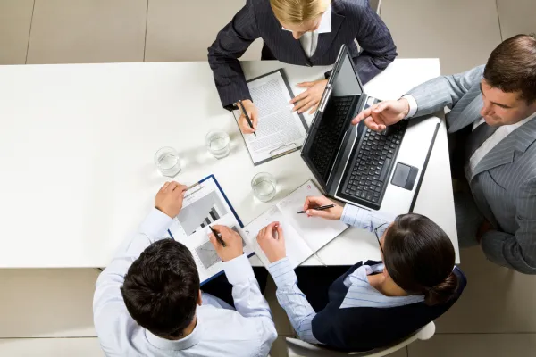 Image of a negotiation table with US and Asian business people, with a background of cultural icons or landmarks.