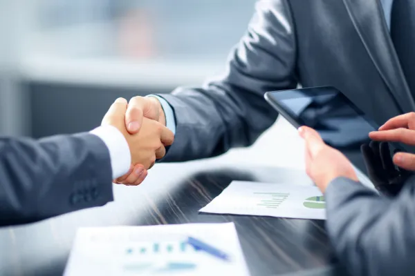 Image of a handshake between a US and Asian business person, with a background of futuristic technology or a global cityscape.