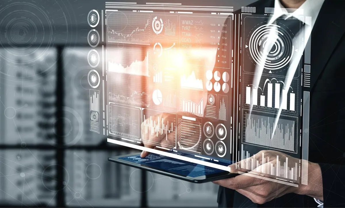 A business professional holding a digital tablet with holographic charts, graphs, and data visualizations projecting above it, symbolizing the integration of artificial intelligence and data-driven insights in modern business strategies.