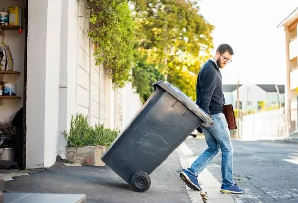 man taking trash out How Often Should You Clean Trash Bins? | Trash Can Cleaning Service in Gilbert