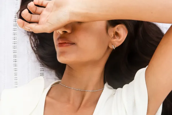 Woman relaxing with arm over face, representing the freedom and privacy of a faceless brand lifestyle.