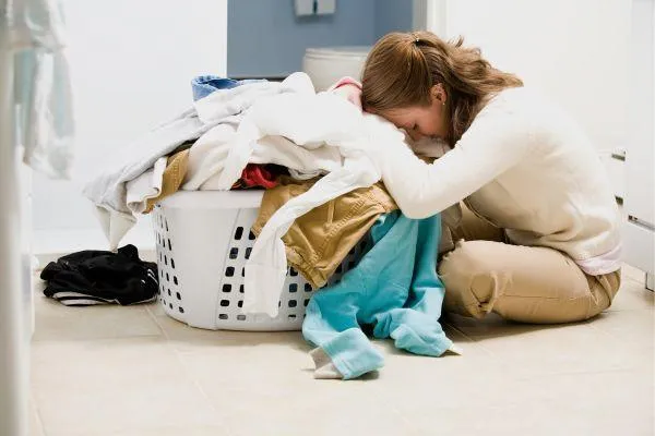 a woman is kneeling on the ground putting laundry in a basket