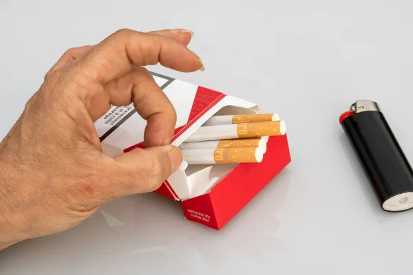 a hand holding a cigarette with lighter