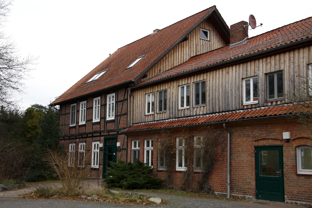 Langes historisches Fachwerk- und Backsteingebäude mit rotem Ziegeldach und grüner Eingangstür.