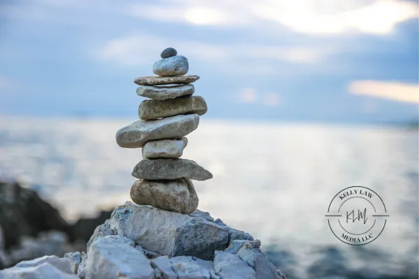 stacked rocks near the ocean with the Kelly Law Media logo