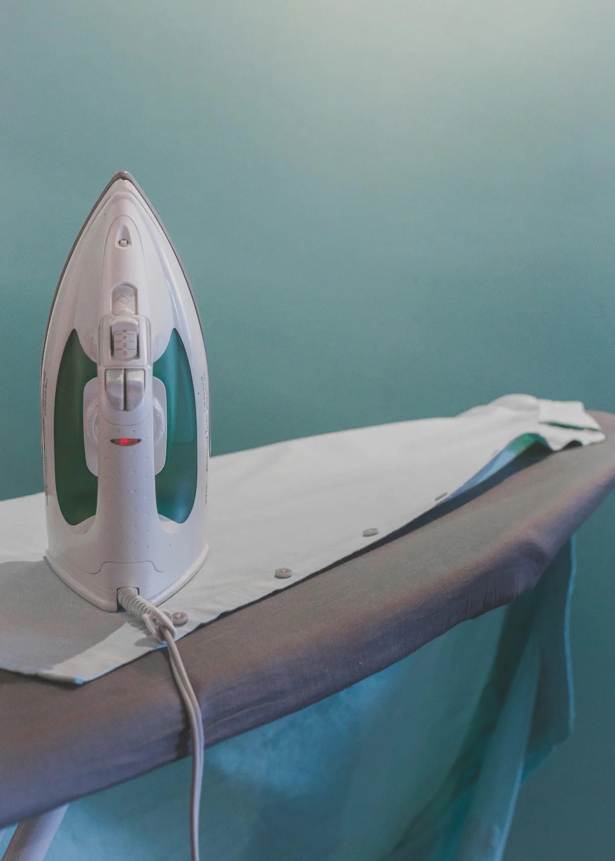 An iron sits on an ironing board and a shirt 