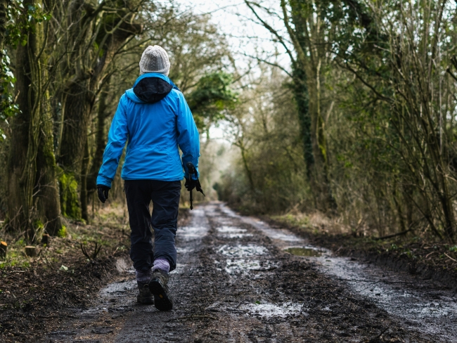 A woman wearing a coat walks through trees