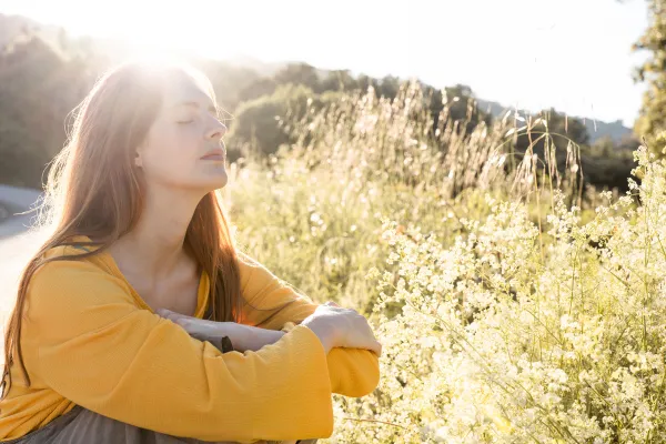 Women in a field enjoying the sun on her face