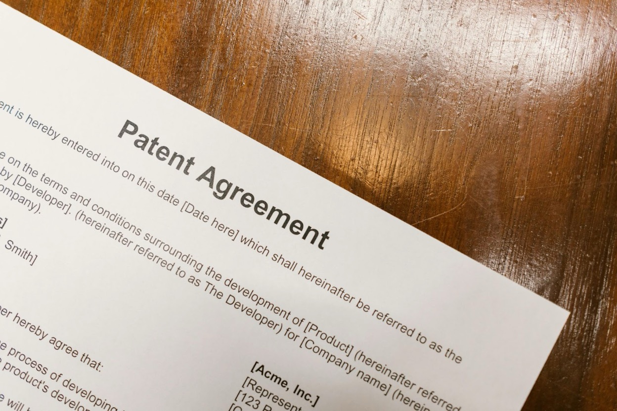 A patent agreement document on a wooden desk
