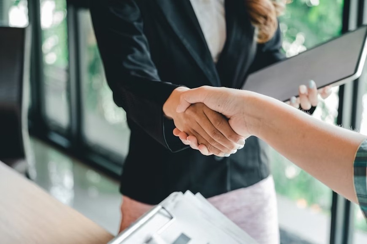 Two professionals having a handshake after signing a license agreement.