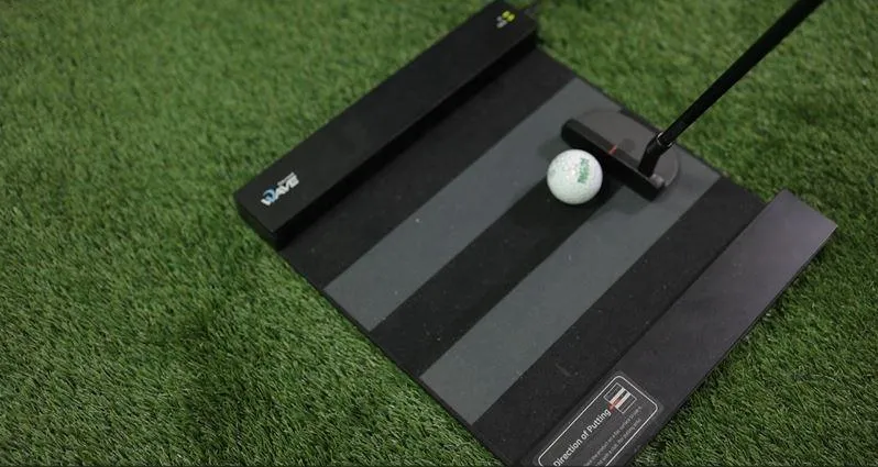 Putting pad in an indoor golf simulator, featuring artificial grass and target holes for practicing putting skills.