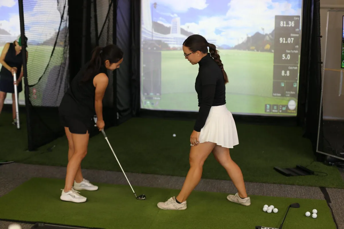 Golf instructor demonstrating proper grip technique for holding a golf club during a lesson at Smash Factor Lounge.