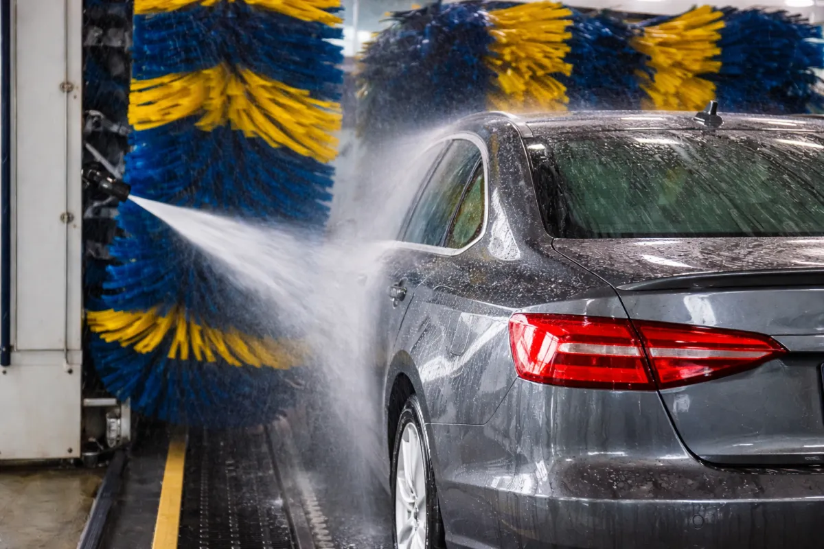Car moving through an automatic car wash as water sprays across the exterior