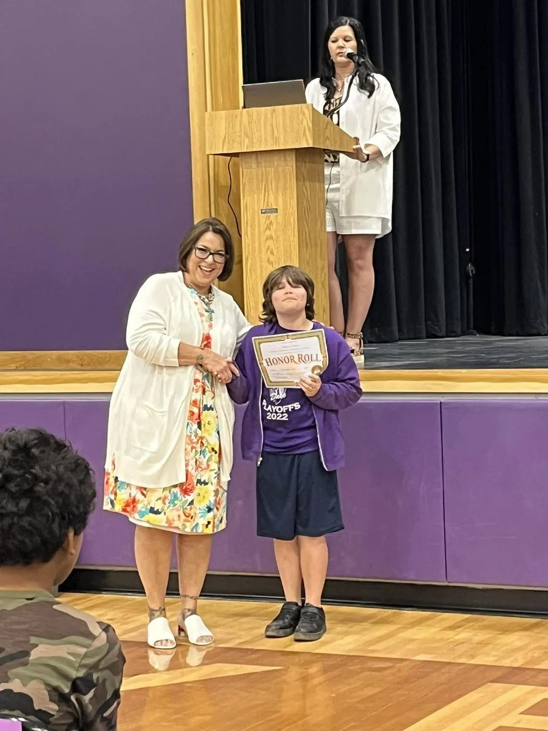 middle school boy receiving award in front of school stage 