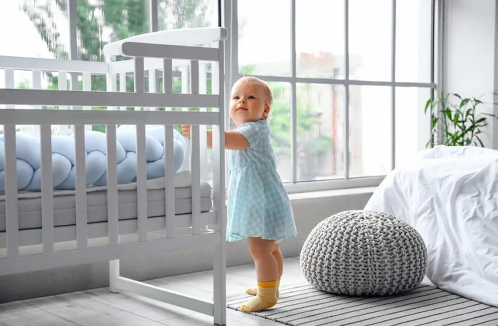 baby standing holding crib