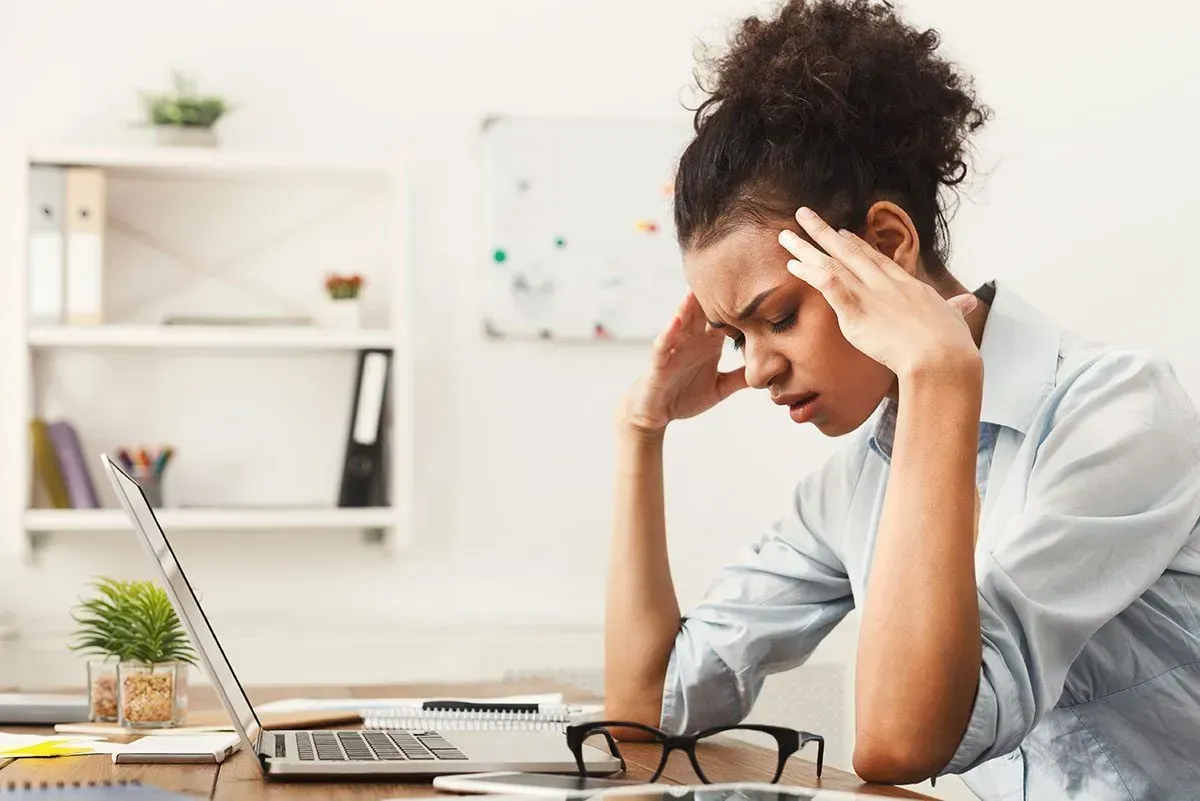 woman sitting a desk in front of her laptop looking stressed out