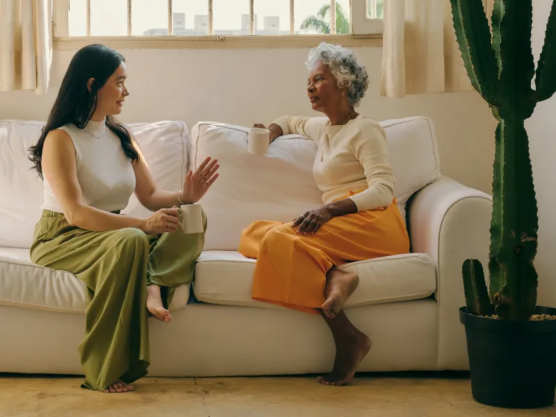 Two women sitting on a couch talking