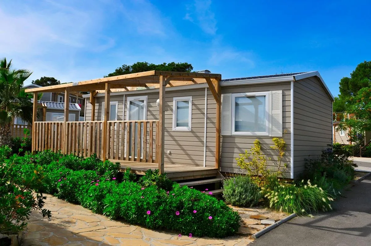 A brown mobile home with a porch.