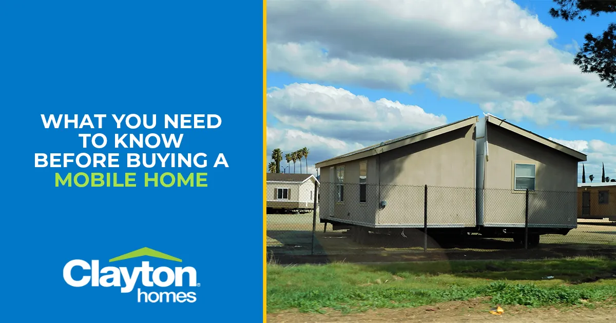 Two separated halves of a double-wide mobile home sits in a grassy field with other homes.