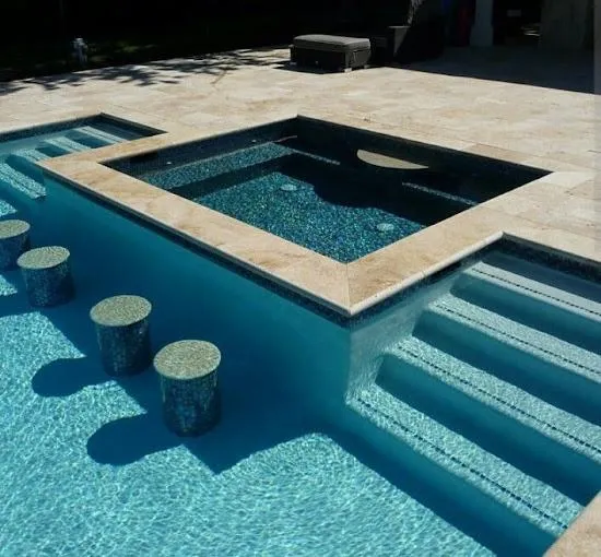 Luxury pool with raised spa and custom tile seating, featuring a stone deck.