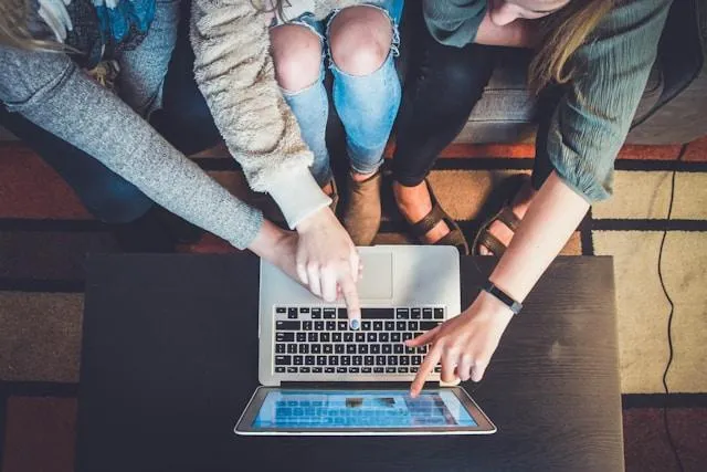 Students talking and pointing a computer