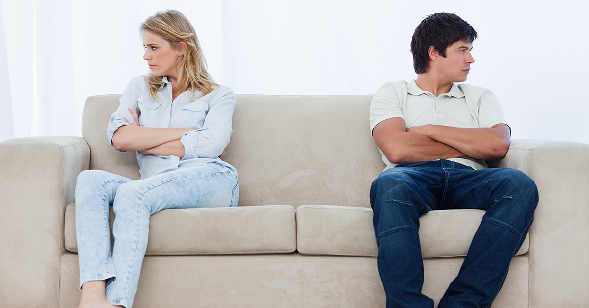 Coppia seduta sul divano in silenzio, segnale di difficoltà nella relazione
