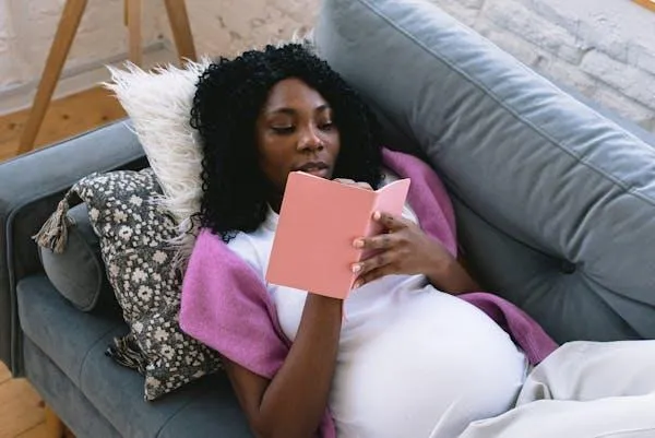 Pregnant woman lying on a couch and writing in a notebook