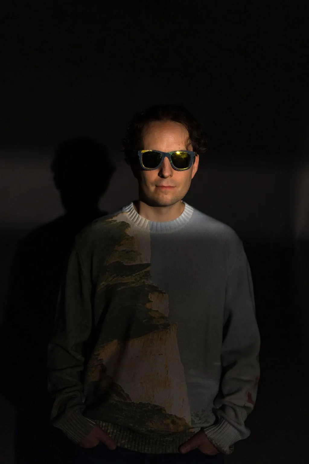 GrayBeat in artistic sweater and shades facing forward, slight smile, hands in pockets