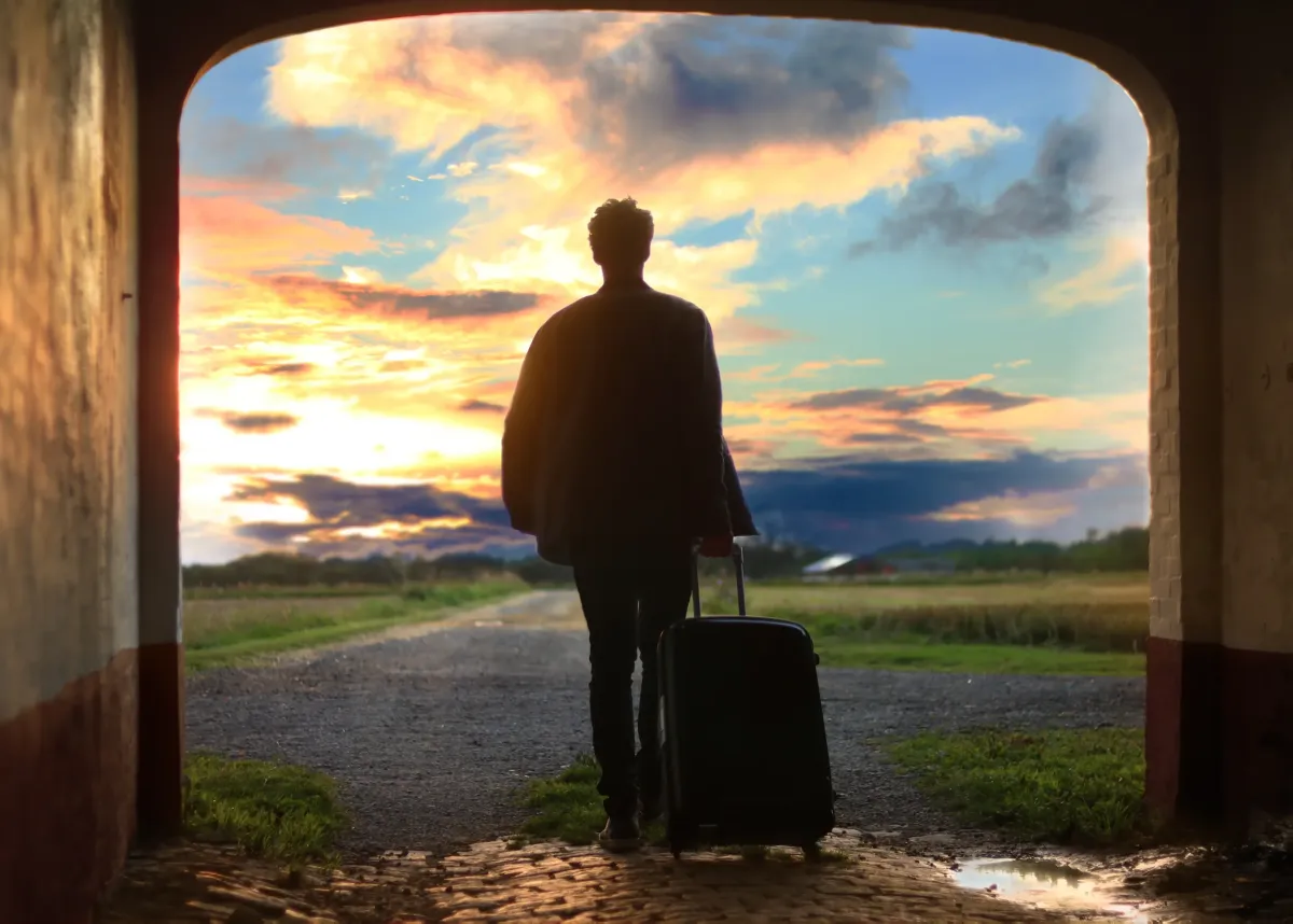 A person walking into the sunset with a suitcase, symbolizing a reflective and empowering weekend getaway.
