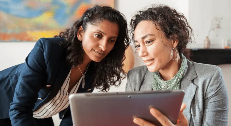 Two woman checking information on a tablet.