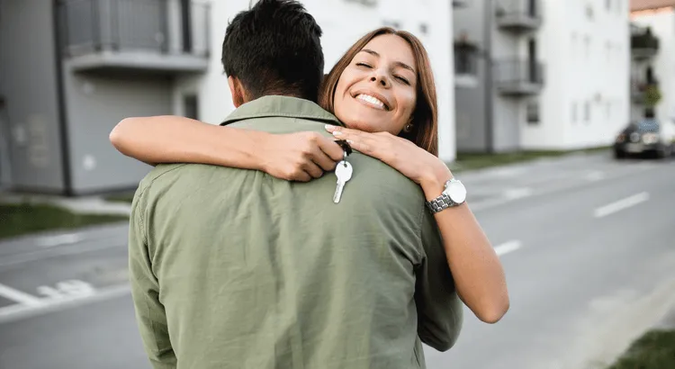 Couple embracing after getting the key of their new home.