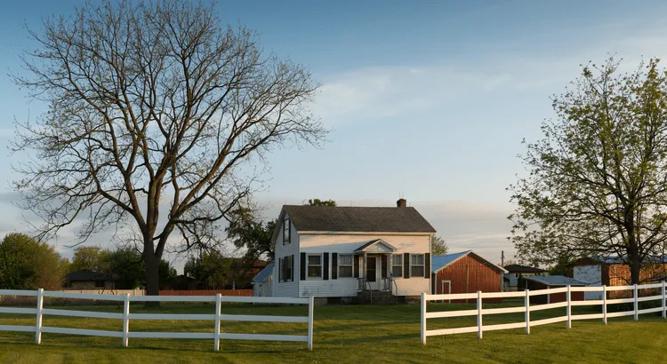 Beautiful country side home with a barn and wooden white fence.