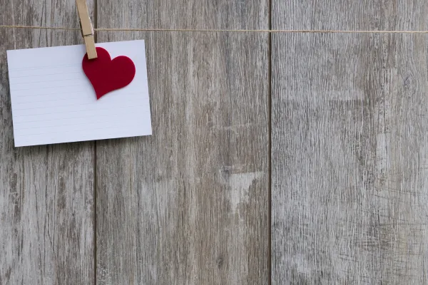 a small note with a red heart pegged to a board