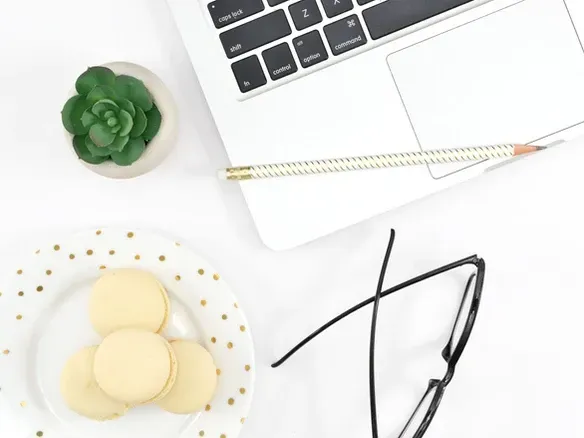 computer, plant, glasses on a flatlay desk