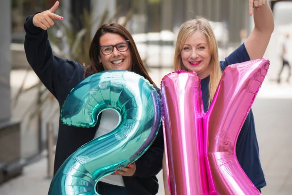 Rachel Allen and Samantha Poole holding helium balloons to show 2,000 members in their Facebook Group