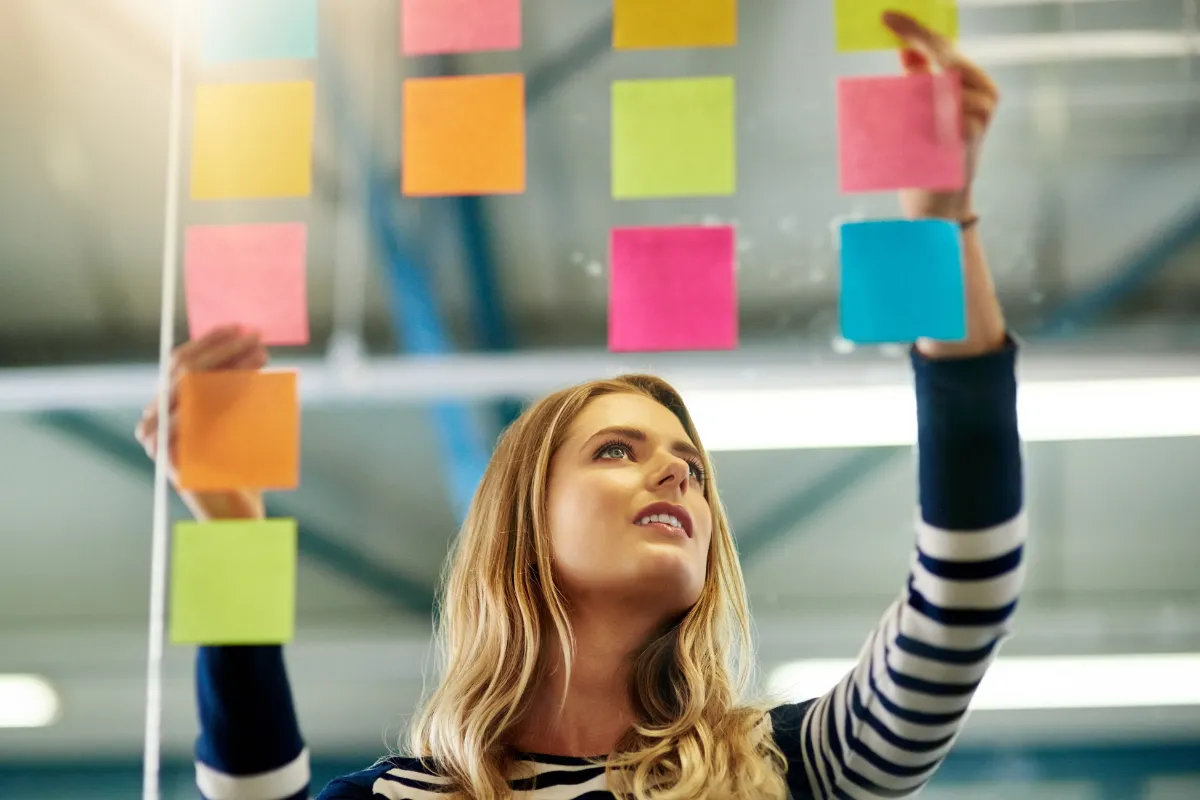 Woman organises post it notes on a board