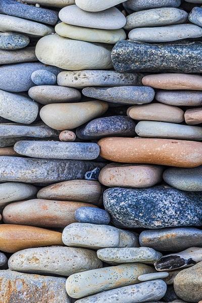 Flat stones of many natural colours are stacked as if making a wall.