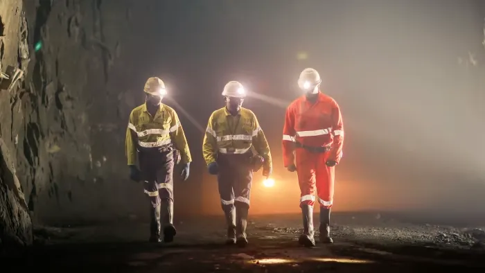 Miners walk through the dark with head lamps