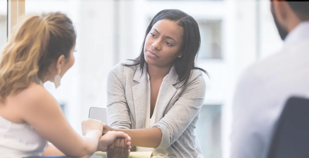 Woman listening with empathy and focus while holding another person’s hand during a conversation.